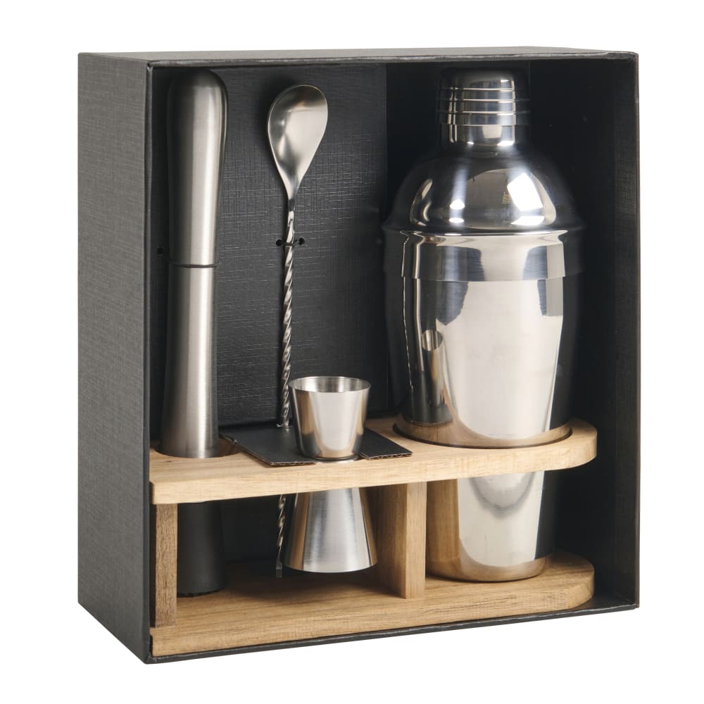 Shaker en inox et accessoires de bar posés sur un support en bois clair, dans un coffret noir