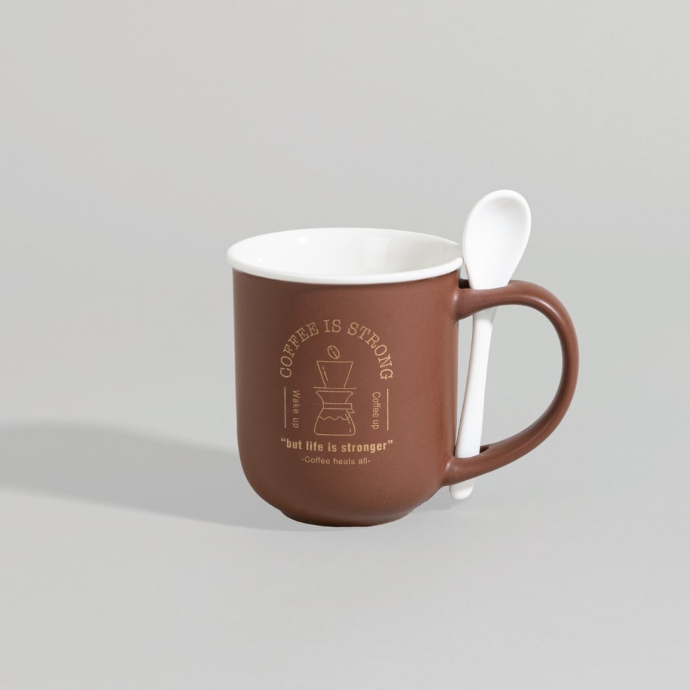 Tasse marron en porcelaine, sa cuillère glissée dans l’anse