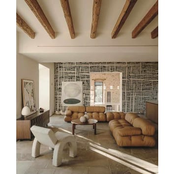 Grand salon aux poutres apparentes, canapé marrons et papier peint geometrique noir et blanc