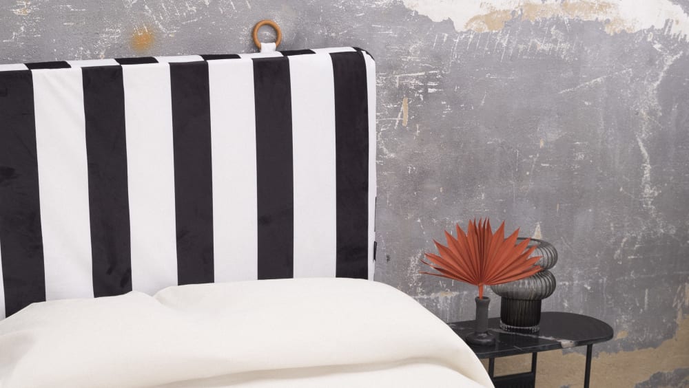 Tête de lit en velours et mousse imprimé à franges blanches et noires.